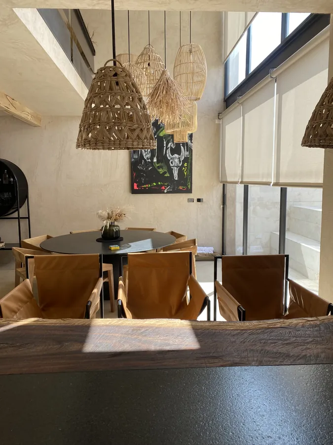 Comedor con lámparas colgantes y muro de piedra — casa residencial construida por Prisma Habita en Puebla