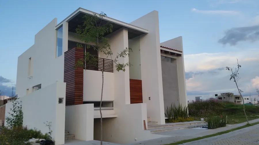 Fachada minimalista blanca al anochecer — casa residencial construida por Prisma Habita en Puebla