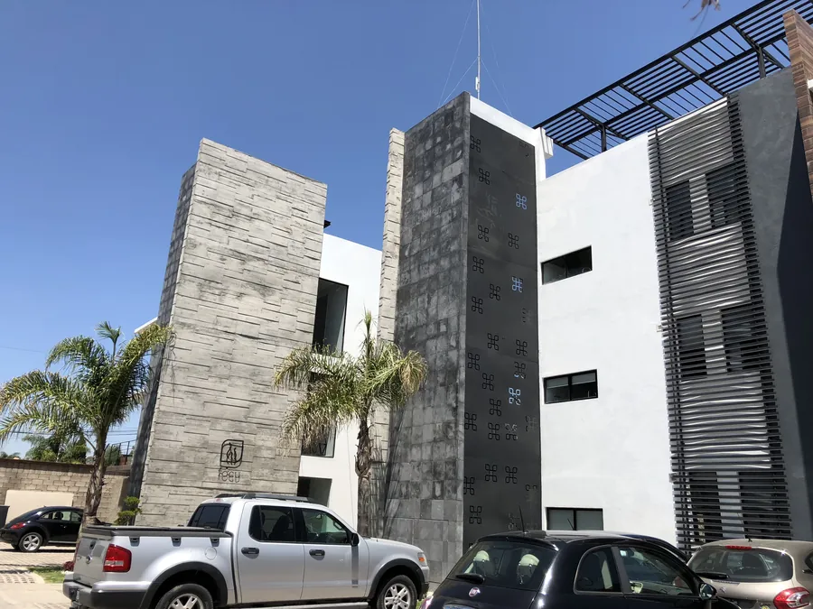 Fachada contemporánea de concreto y piedra de tres niveles — casa residencial construida por Prisma Habita en Puebla