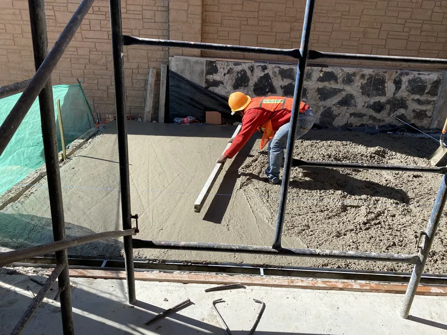 Obrero extendiendo material en colado de losa — proceso de construcción de casa residencial en Puebla