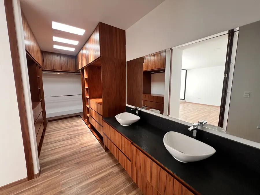Baño de madera con tragaluz y doble lavabo de piedra — residencia contemporánea de doble altura en Puebla