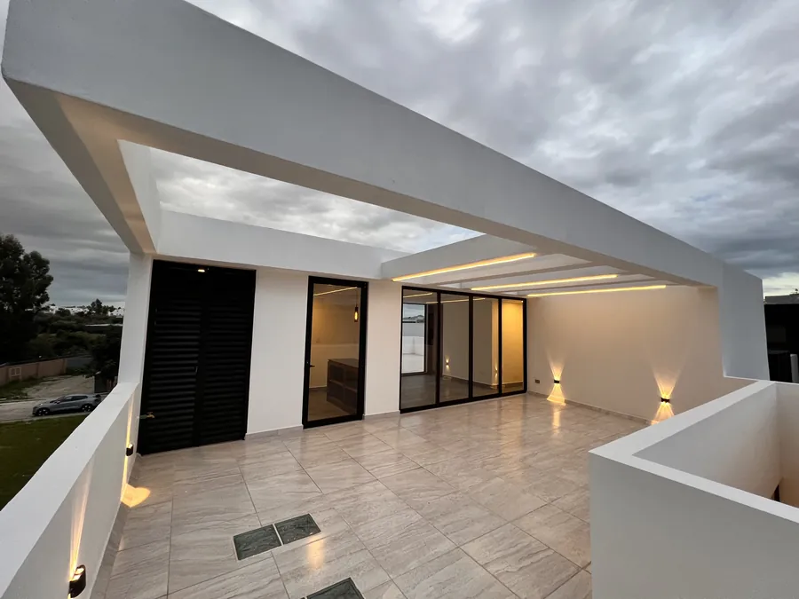 Estancia abierta a terraza al anochecer — residencia contemporánea de doble altura en Puebla