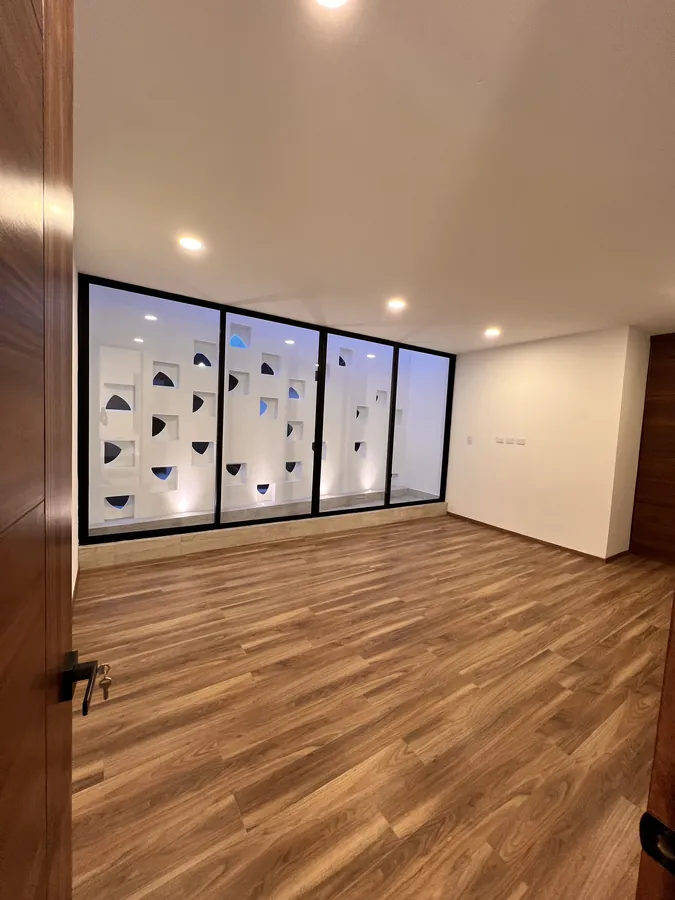 Recámara con piso de madera y ventanal de celosía — residencia contemporánea de doble altura en Puebla