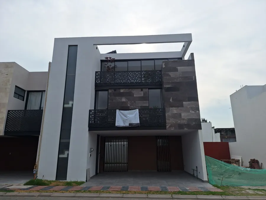 Fachada de tres niveles con piedra oscura y herrería — casa Missouri 99 en el corredor Angelópolis, Puebla