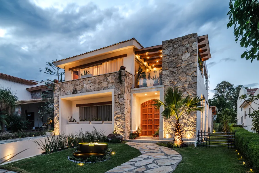 Fachada de piedra iluminada de noche con andador — casa residencial de autor en Atlixco, Puebla