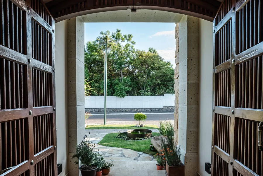 Portal de arco de cantera enmarcando el jardín — casa residencial de autor en Atlixco, Puebla