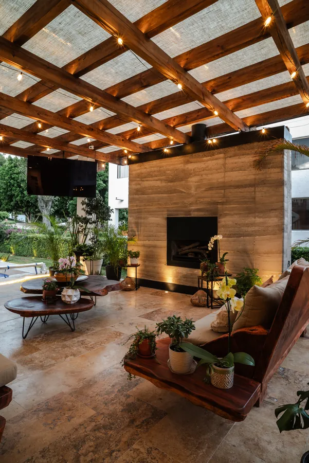 Sala exterior bajo pérgola con chimenea — casa residencial de autor en Atlixco, Puebla