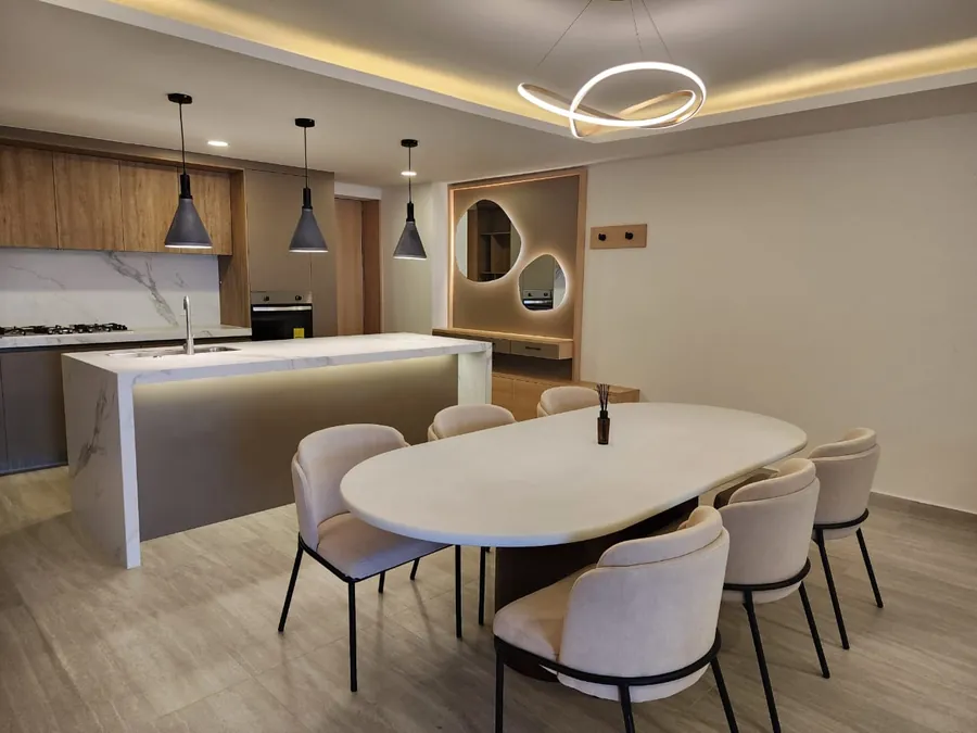 Comedor con mesa oval, mármol y espejo circular — penthouse en Lomas de Angelópolis, Puebla